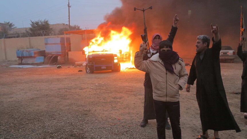 Islamic insurgents burn a police vehicle in Ramdi, Iraq.