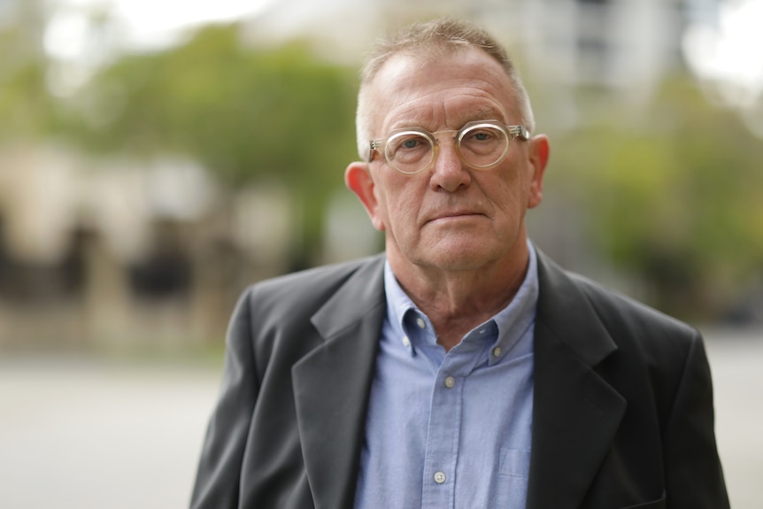 A middle-age man wearing a jacket, shirt and glasses poses in a head-and-shoulders photo.