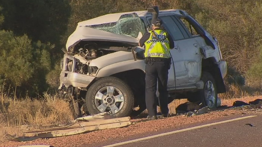 A police officer examines one of the four-wheel drives involved in a head-on crash that killed two people near Whyalla.