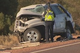 A police officer examines one of the four-wheel-drives involved in a head-on crash that killed two people near Whyalla.