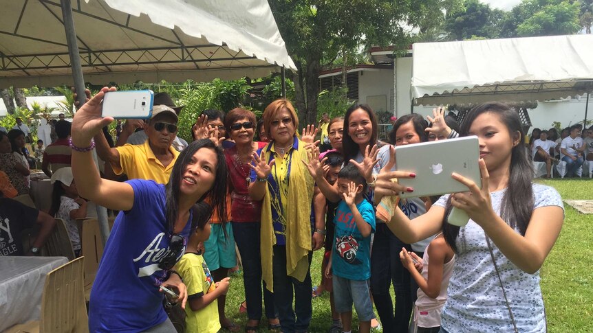Senator Leila de Lima poses for a casual photo with a large group of people of various ages.