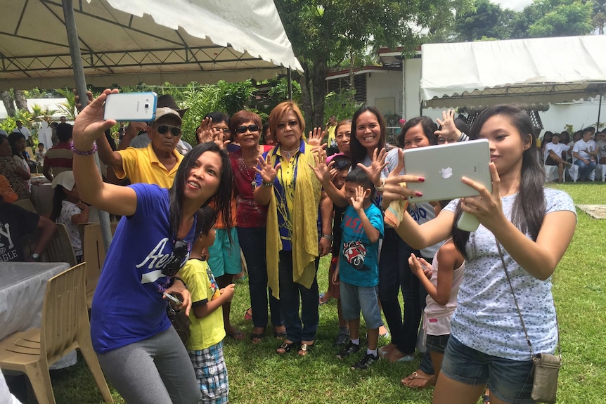 Senator Leila de Lima poses for a casual photo with a large group of people of various ages.
