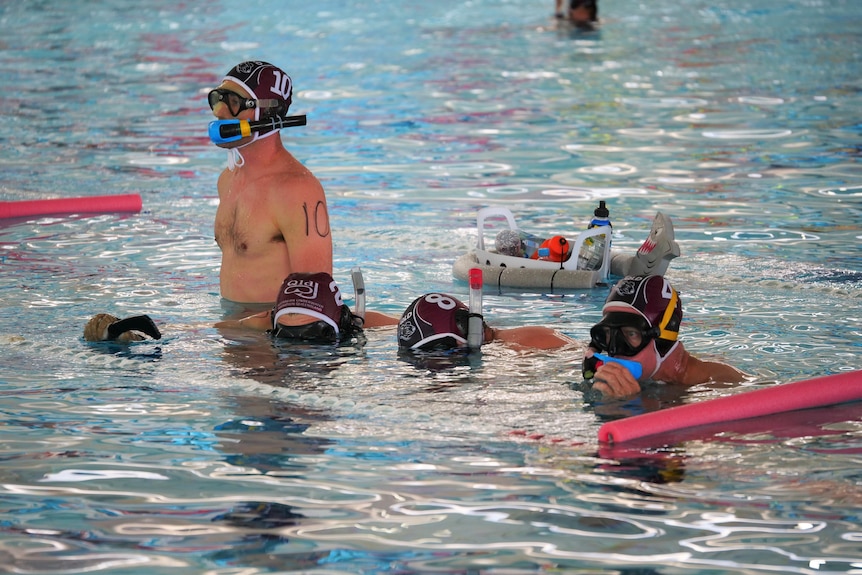 Un groupe de nageurs se tient dans une piscine portant des masques et des lunettes