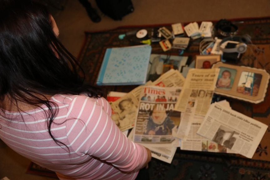 A woman looks over a table of newspaper articles