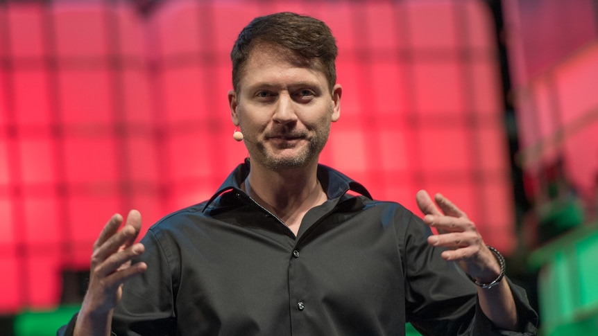 A man wearing a black shirt on stage wearing a wireless headset microphone