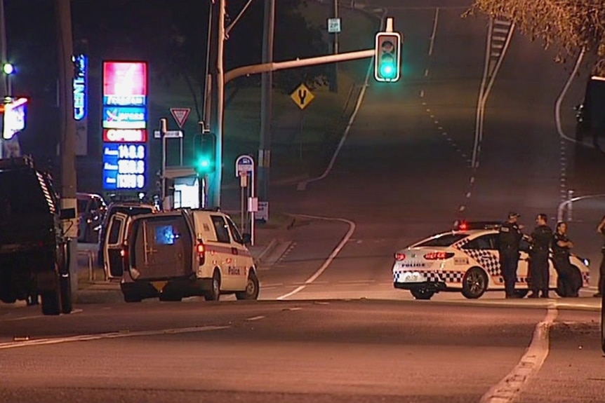 Police blocking the street outside a petrol station at night