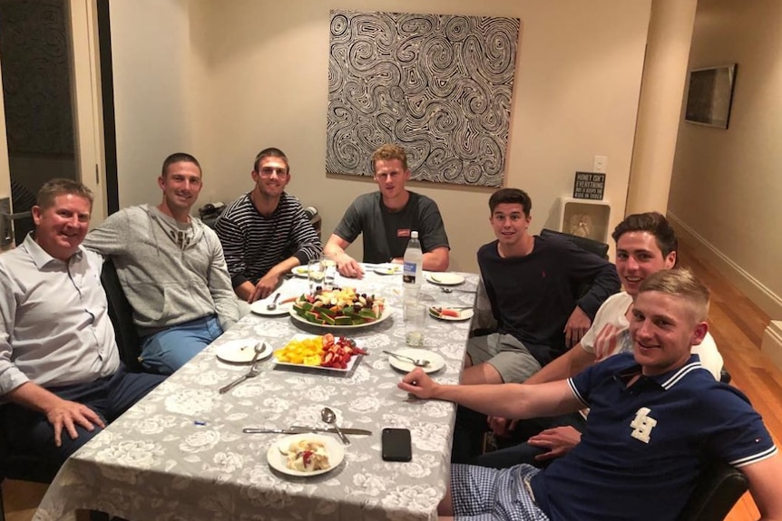 SA Liberal MP Terry Stephens sits at a dinner table with football and cricket players.