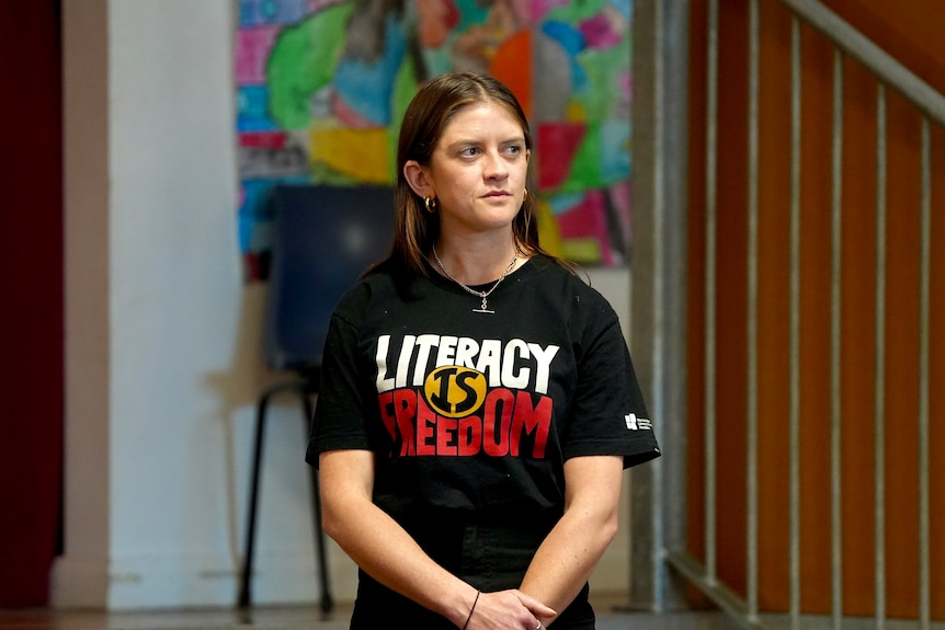 A white woman with long dark hair wearing a black shirt which says Literacy is Freedom