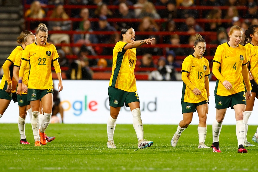 Australi's women's football team walking up the pitch, with Sam Kerr in the centre pointing and directing her teammates.