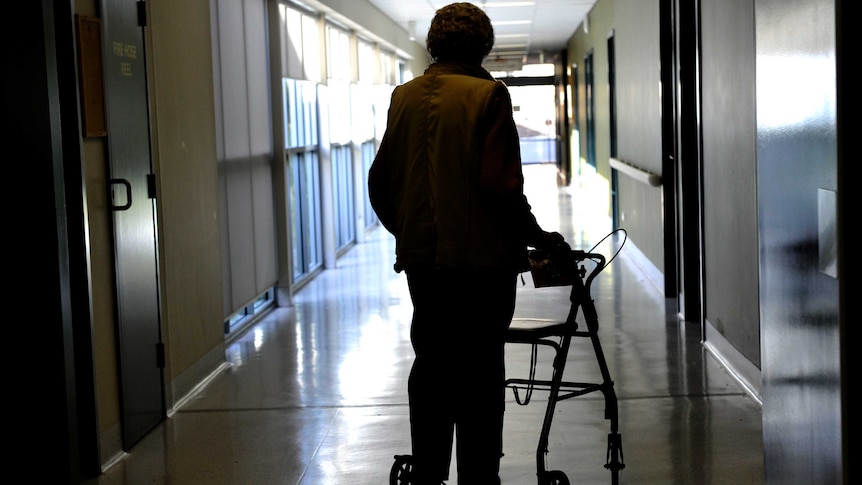 A woman in silhouette using a mobility walker.