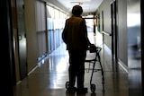 A woman in silhouette using a mobility walker.