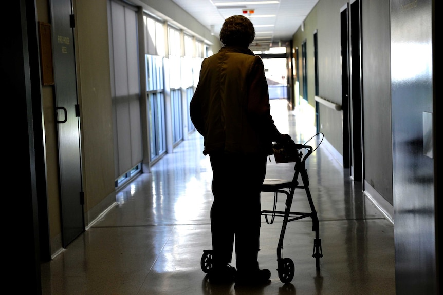 A woman in silhouette using a mobility walker.