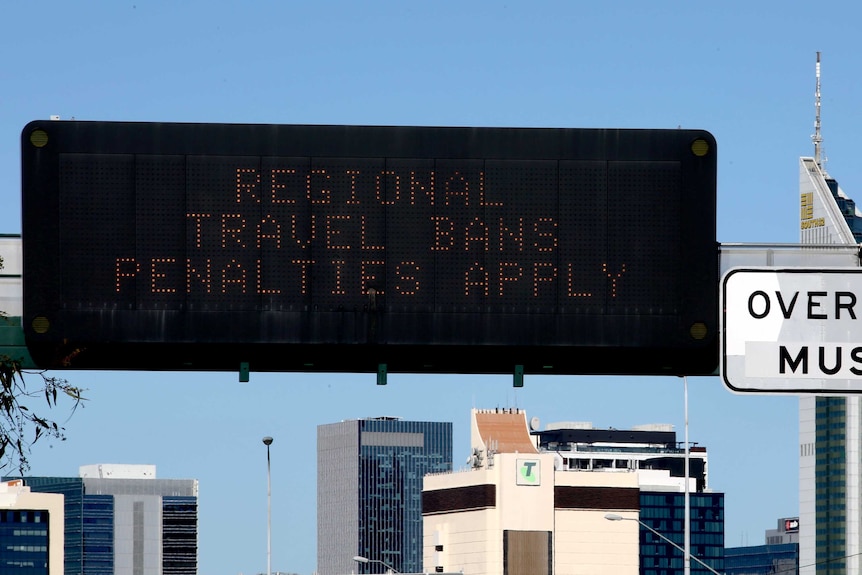A sign above the Mitchell Freeway southbound, before Perth, warns drivers of a regional travel ban