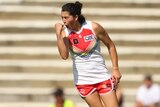 A Sydney Swans AFLW player pumps her fist as she celebrates a goal.