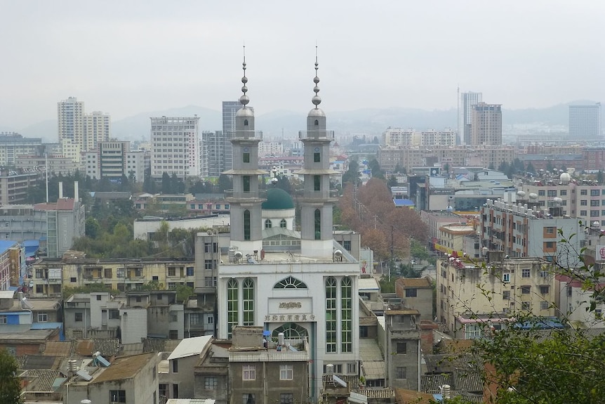 A mosque is shown in the foreground of a smoggy Chinese city.