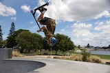 13-year-old boy Zeth Bennett performs a backflip on a scooter over the lip of a skate bowl