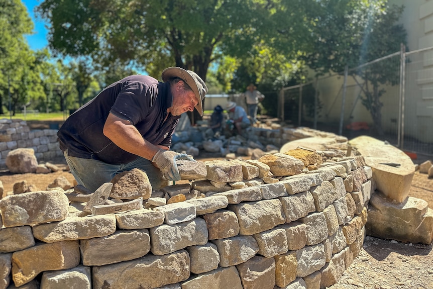 A man works on a dry stone wall