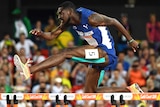A runner leaps over a hurdle