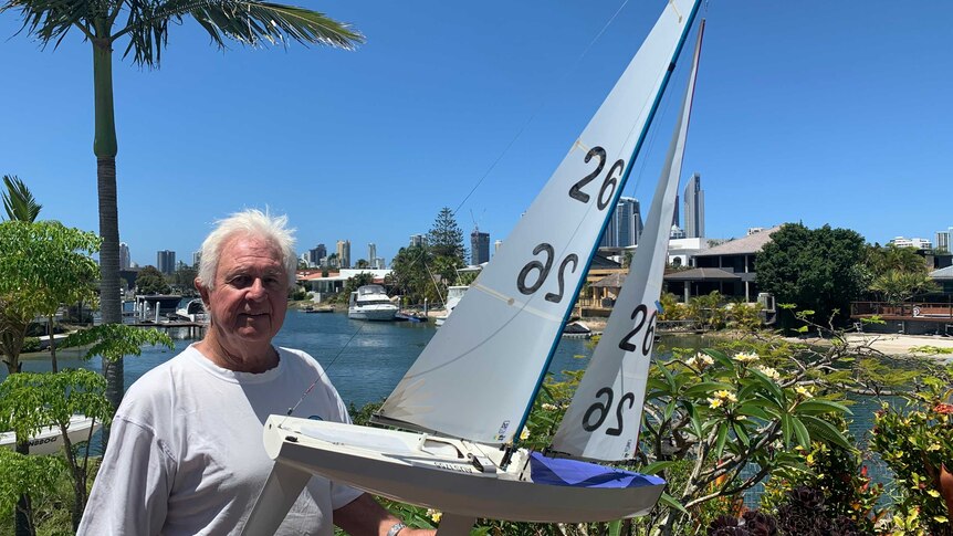 Radio yacht enthusiast Allan Walker holding his boat near a Gold Coast canal