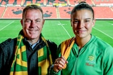 Alen Stajcic and Chloe Logarzo wear Matildas scarves as they stand on the terraces of Penrith Stadium with the field behind them