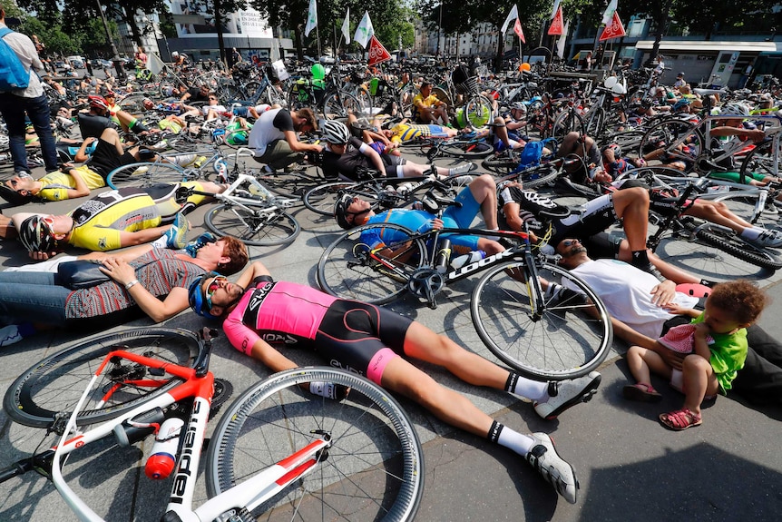 Cyclists lay on the ground during a gathering to prevent bike accidents in Paris