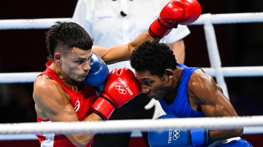 Man in red singlet punches man in blue singlet in boxing match