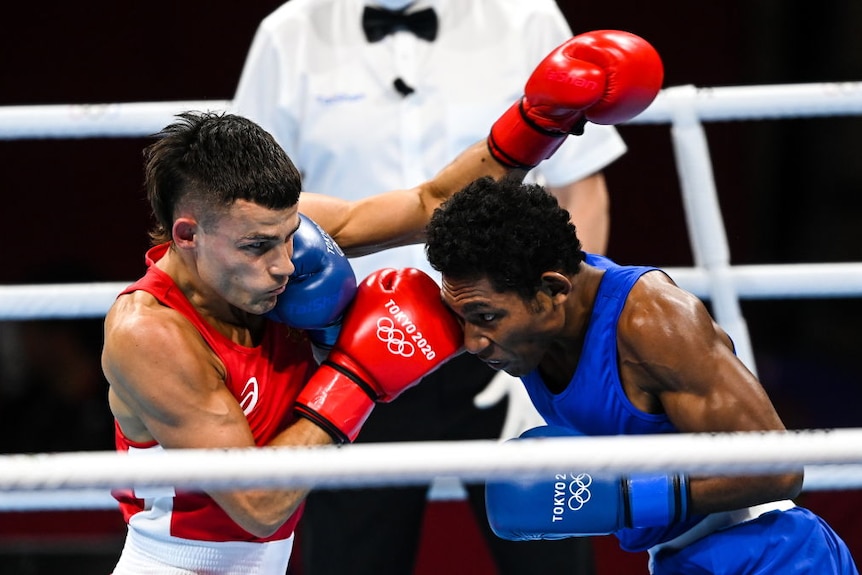 Man in red singlet punches man in blue singlet in boxing match