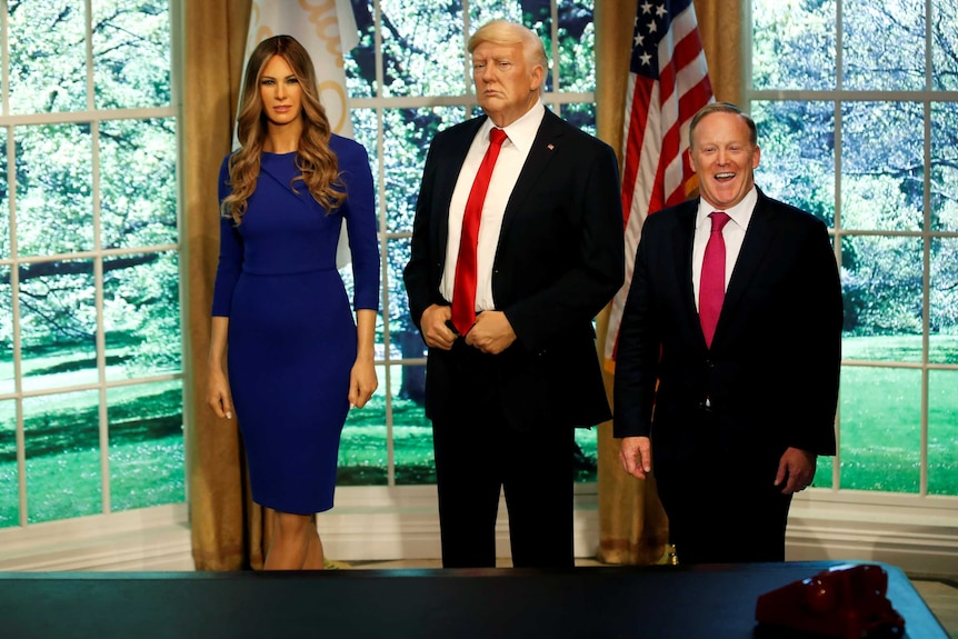 Sean Spicer with wax figures of Melania Trump and Donald Trump.