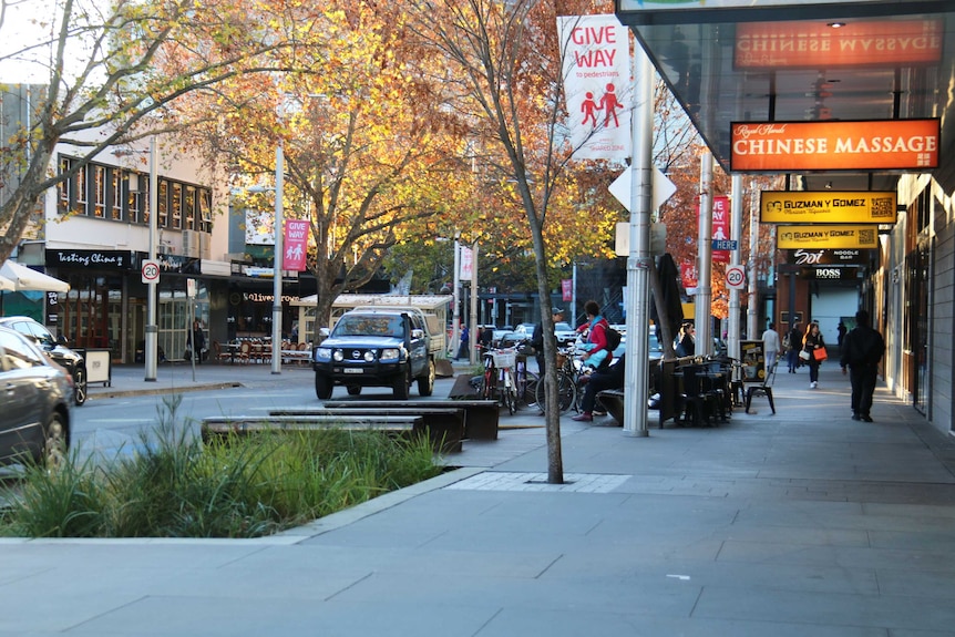 Shoppers and cars moving through Bunda Street near Garema Place, Civic, Canberra.