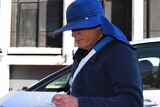David Eastman's face is obscured by a large hat as he steps out of a car.