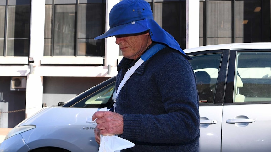 David Eastman's face is obscured by a large hat as he steps out of a car.