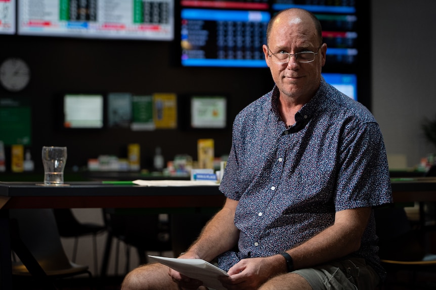 A man sits on a chair looking serious