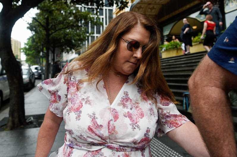 Debbie Malone holds a man's hands as they walk on a city street.