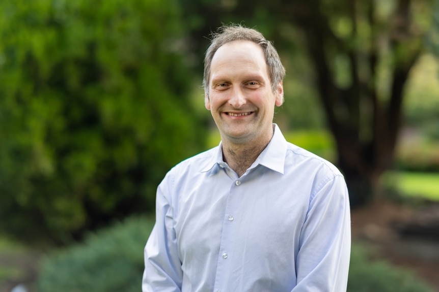 Dr Darren O'Donovan, in a white business shirt, smiles at the camera