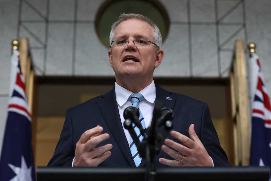 Scott Morrison announces his new ministry speaking with Australian flag behind