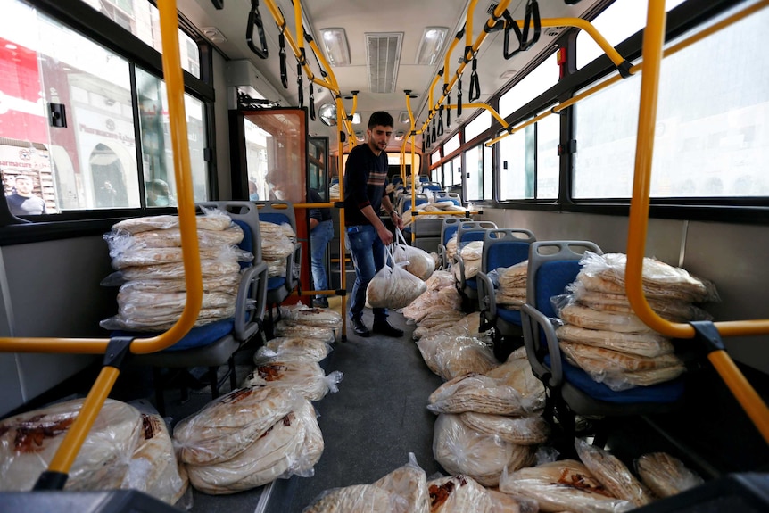 A man boards a bus packed with stacks of flat breads in Jordan