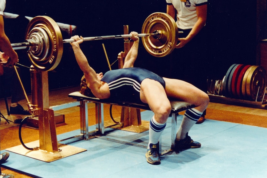 a woman bench presses a huge weight