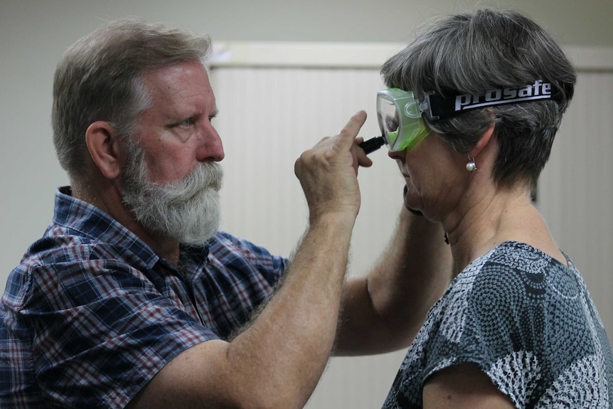 A man places safety goggles on a woman's face