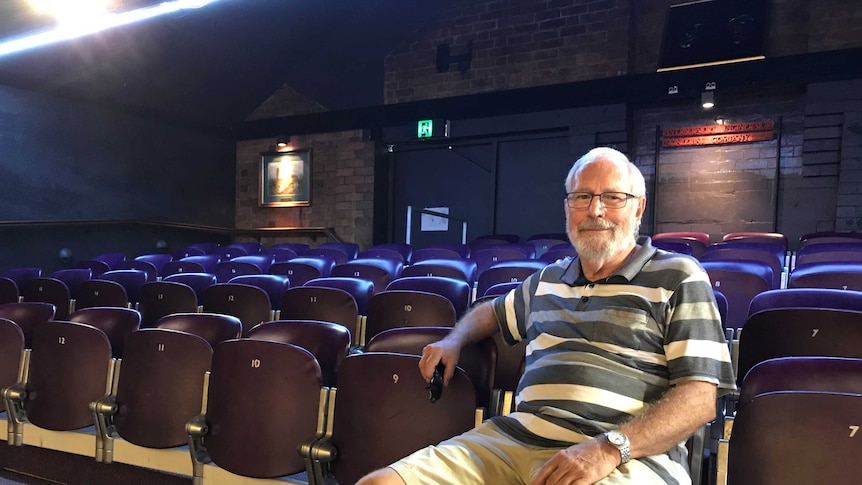 Man sits on seats in a theatre