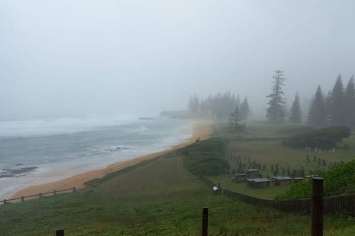 a wide shot of a bay on norfolk island with heavy rain and thick grey clouds
