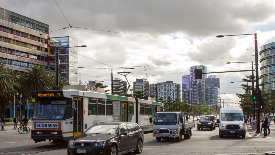 A tram, people, office buildings and high rises, cars.