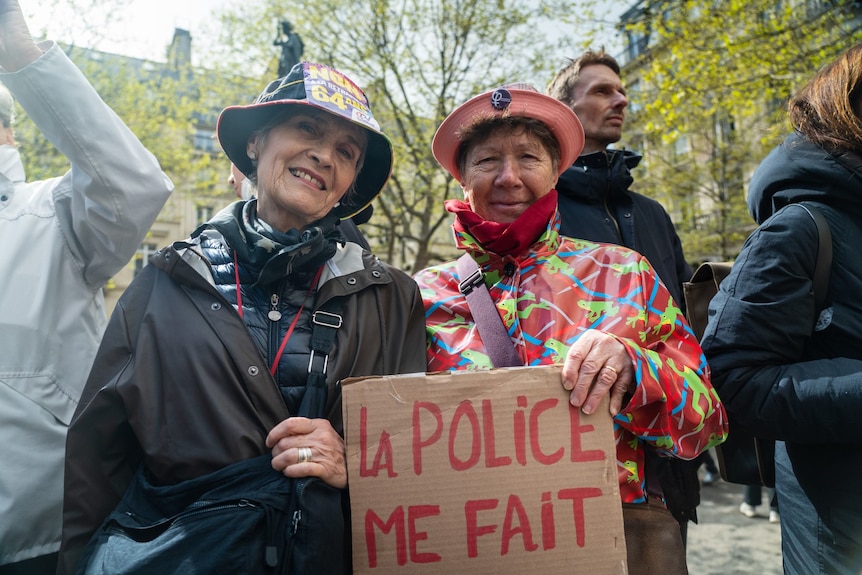 Two women in hats and raincoats protest