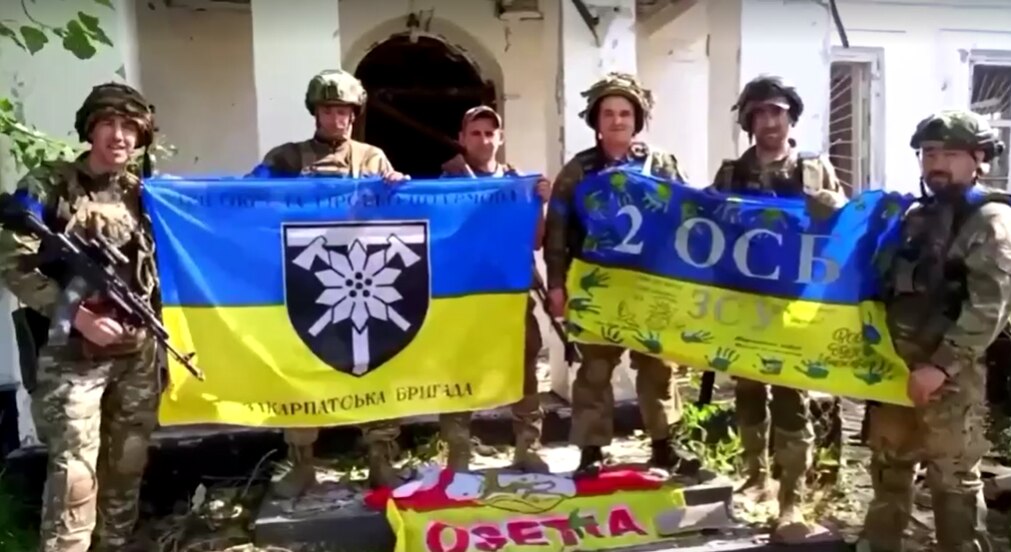 Ukrainian soldiers hold up yellow-and-blue national flags.