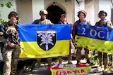 Ukrainian soldiers hold up yellow-and-blue national flags.