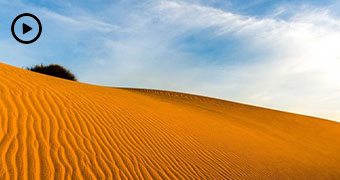 A large sand dune against a blue sky.