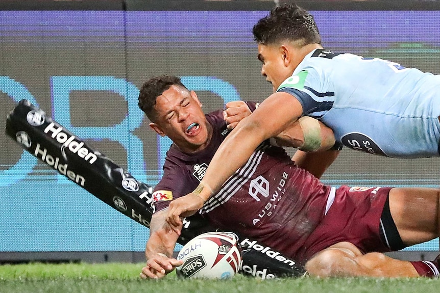 Dane Gagai puts the ball down in the corner while hitting the corner post and being tackled by Latrell Mitchell