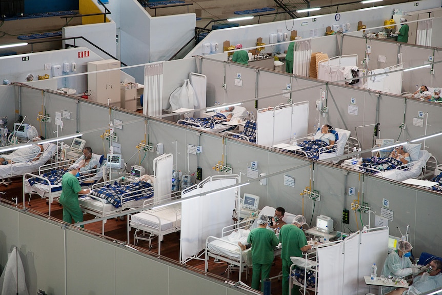 Rows of hospital beds in a gymnasium 