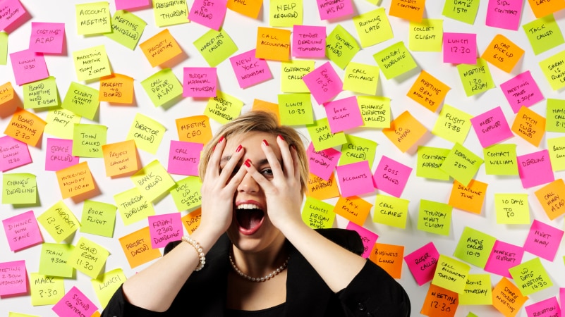 Woman stressed at work surrounded by sticky notes
