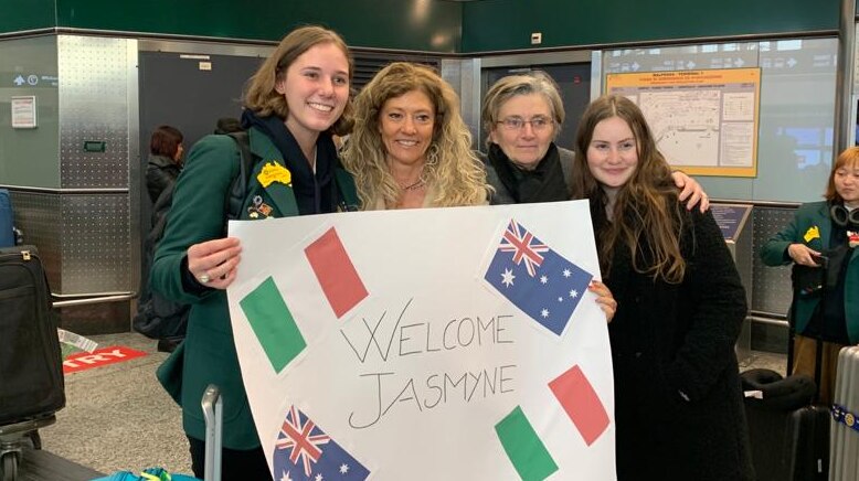 Jasmyne Paull stands with three women who hold a sign with the Italian/Australian flags which says "Welcome Jasmyne"