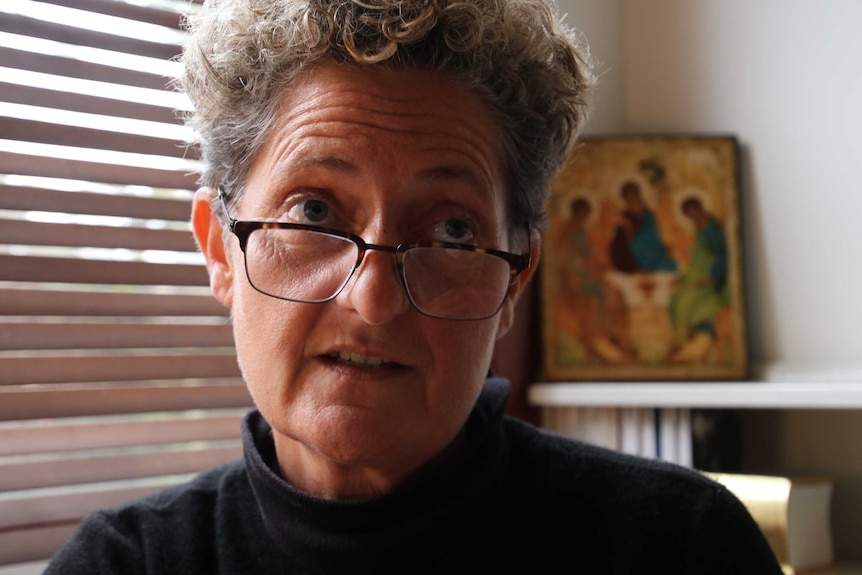 Kate Engelbrecht looks above the camera, with religious iconography in the background.